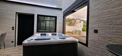 a large bath tub in a room with a large window at Chalet 3 romantique avec jacuzzi in Saint-Louis