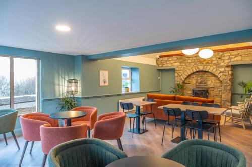 a restaurant with tables and chairs and a fireplace at Otter Hostel Connemara in Leenaun