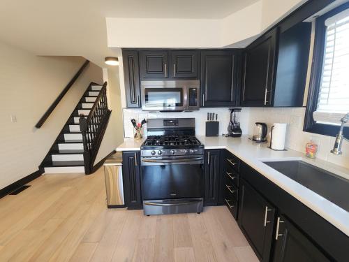 a kitchen with black cabinets and a stove top oven at Chic Haven- Close to Beach, Boardwalk & Casinos in Atlantic City