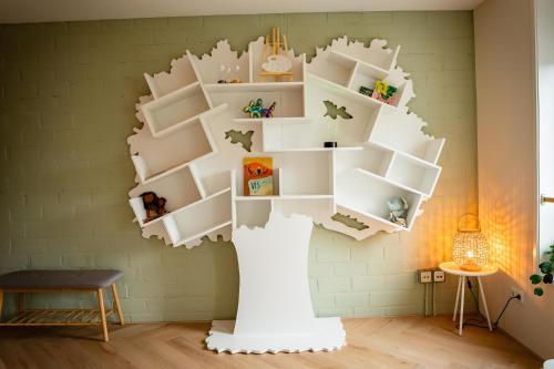 a room with a white tree shaped wall with shelves at Ouder-kind B&B Droomzacht - Natuurkamer in Epe