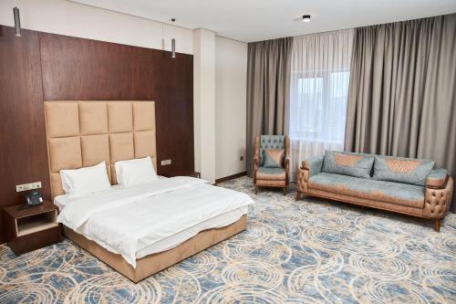 a bedroom with a bed and a couch and a chair at Vogue hotel in Almaty