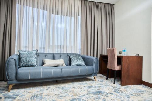 a living room with a blue couch and a desk at Vogue hotel in Almaty