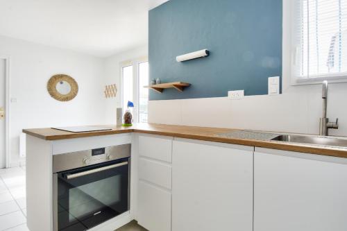 a kitchen with white cabinets and a sink at Maison pour 6 - Jardin - Centre de Noirmoutier in Noirmoutier-en-l'lle
