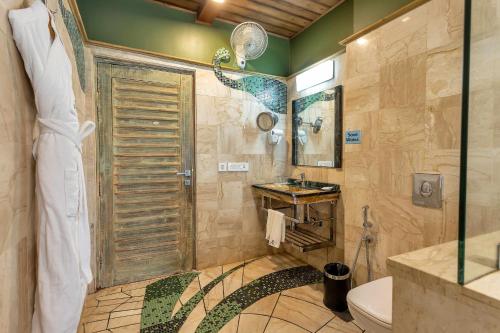 a bathroom with a shower and a toilet and a sink at The Baga Beach Resort in Baga
