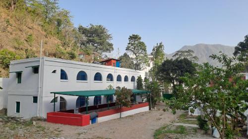 a white building with a green roof next to a hill at Swami Samarpan Ashram in Rishīkesh