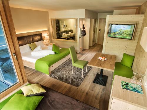 a small bedroom with a green bed and a couch at Alpin Juwel - Bio und Lifestylehotel in Saalbach Hinterglemm