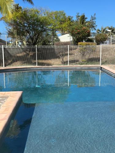 a swimming pool with blue water in front of a fence at Studio & piscine in La Saline les Bains