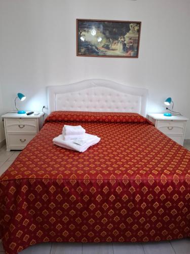 a bed with a red comforter with two towels on it at Le Maschere in Mestre