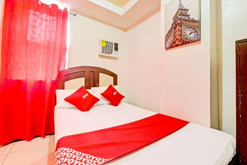 a bedroom with a bed with red pillows and a clock at OYO 894 Cosmo Hotel P Campa Manila in Manila