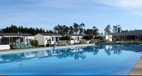 a large blue swimming pool with houses in the background at BUNGALOW E10 na lands hause in Pataias