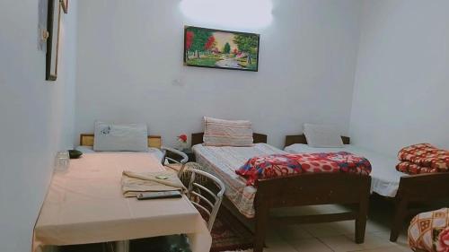 una habitación con dos camas y una mesa y sillas en SOLAN HOSTELz, en Solan