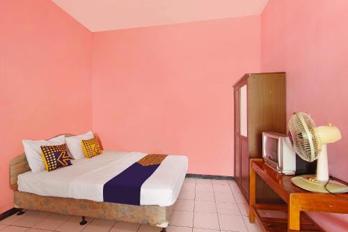 a bedroom with a bed and a tv in it at Hotel O Meilias in Cilacap