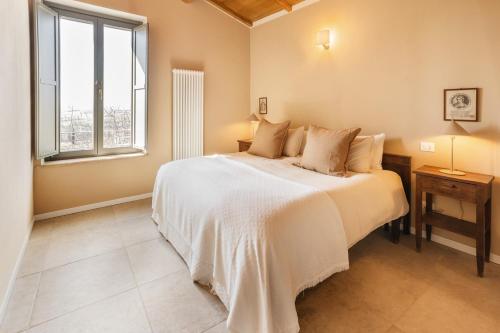 a bedroom with a large white bed and a window at Retrocantina Antonelli in Montefalco