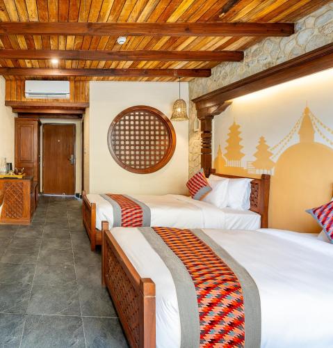 three beds in a room with wooden ceilings at Temple Bell Boutique Hotel & Spa in Pokhara