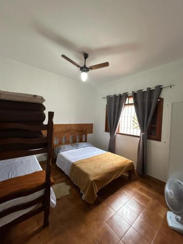 ein Schlafzimmer mit zwei Betten und einem Deckenventilator in der Unterkunft Casa Praia Grande pé na areia in Praia Grande