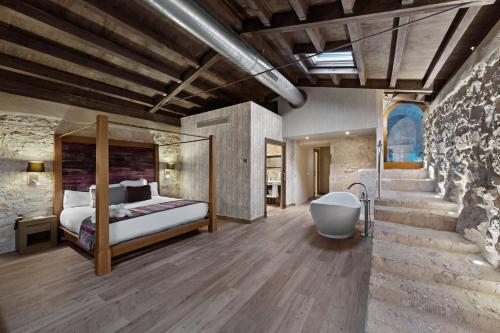 a master bedroom with a bed and a bath tub at Castilla Termal Monasterio de Valbuena in Valbuena de Duero