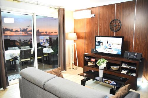 un soggiorno con un divano e una televisione di T2 classé 4 étoiles avec jardin, piscine, vue mer à Saint-Gilles-les-Bains a Saint-Gilles-les Bains