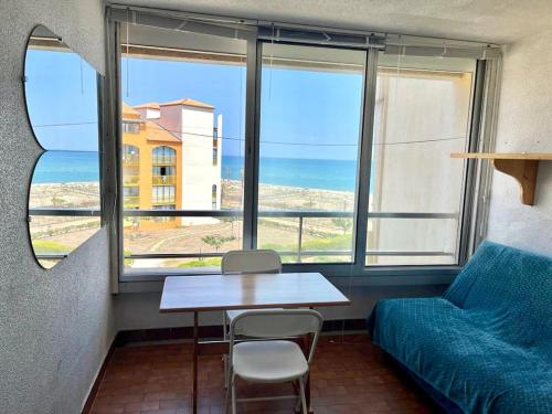Cette chambre comprend une table, un canapé et une fenêtre. dans l'établissement Bright studio with sea view, au Barcarès