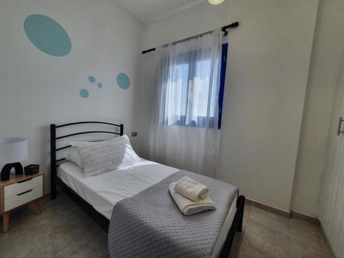 a small bedroom with a bed and a window at Aeon Blue in Sikinos