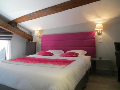 a bedroom with a large bed with a pink headboard at Auberge Bressane de Buellas in Buellas