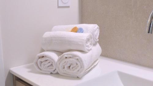 - une pile de serviettes assises sur un comptoir dans la salle de bains dans l'établissement Ty Eglantines - confortable maison neuve proche des plages, à Étel