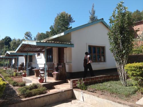 a man walking in front of a small white house at Kanani Home Stay in Lushoto