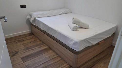 Una cama con sábanas blancas y dos toallas. en Passive House con piscina y jardín privado, en Novo Sancti Petri