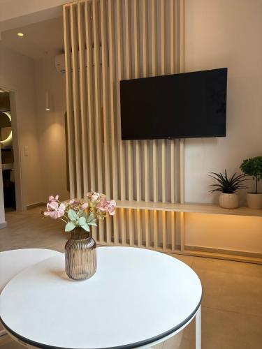 a living room with a white table and a television on a wall at Maya Suites Potidaia in Nea Potidaea