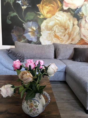 a vase with flowers on a coffee table in front of a couch at RosenSuite SGH in Sangerhausen