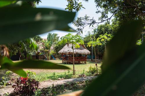 a hut with a grass roof in a park at Le Soleil Kep - Surya Kep in Kep