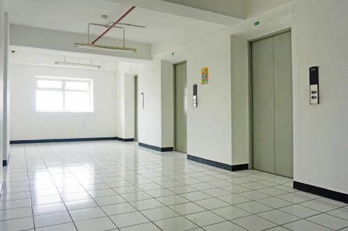 an empty hallway with white walls and white tile floors at OYO 91593 San San Rooms Apartment Gunung Putri Square in Parungdengdek