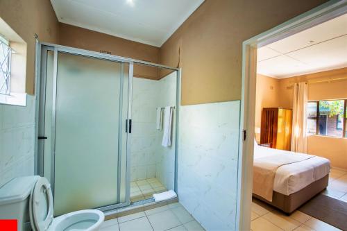 a bathroom with a shower and a toilet and a bed at Victoria Falls Premier Lodge in Victoria Falls