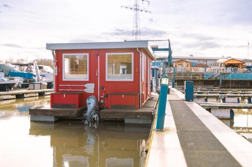 a small red house on a dock in the water at Hausboot im Yachthafen Merzig in Merzig