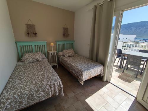 a bedroom with two beds and a balcony at Apartment Mar&Mar with terrace 50m from the beach in Caleta de Sebo
