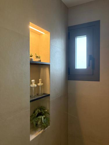 a bathroom with a window and a plant on a shelf at Maya Suites Potidaia in Nea Potidaea