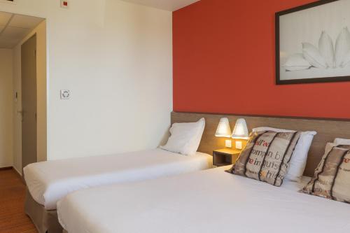 two beds in a hotel room with red walls at Ace Hotel Troyes in Saint-André-les-Vergers