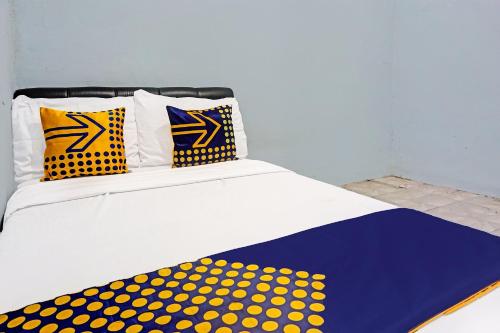 a bed with yellow and blue polka dot sheets and pillows at OYO Life 91600 Syariah Army Kost & Homestay in Gresik