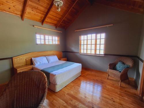 a bedroom with a bed and two chairs in it at Strathavon Cottage in Machadodorp