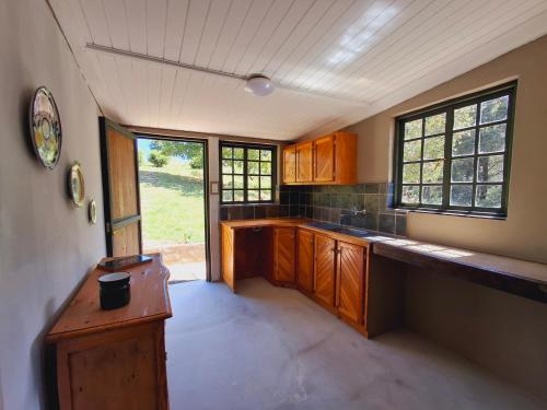 an empty kitchen with wooden cabinets and a window at Strathavon Cottage in Machadodorp
