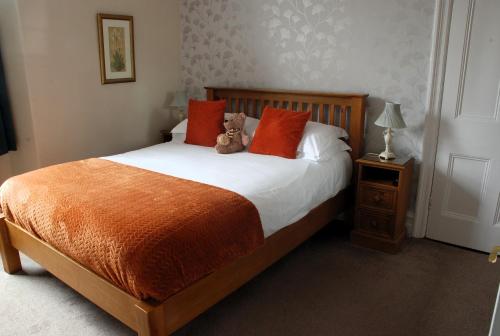 a bedroom with a bed with a teddy bear sitting on it at Denehurst Guest House - Adults Only in Windermere