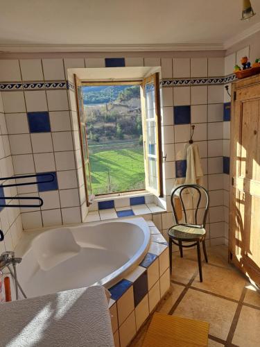 La salle de bains est pourvue d'une baignoire, d'une fenêtre et d'une chaise. dans l'établissement Grande et confortable maison familiale et sa source !, à Eygluy