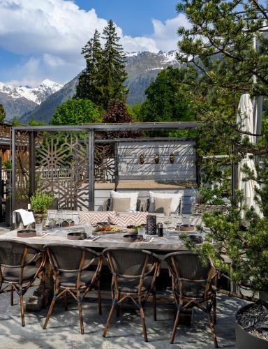 a table and chairs on a patio with mountains at Hotel Piz Buin Klosters in Klosters