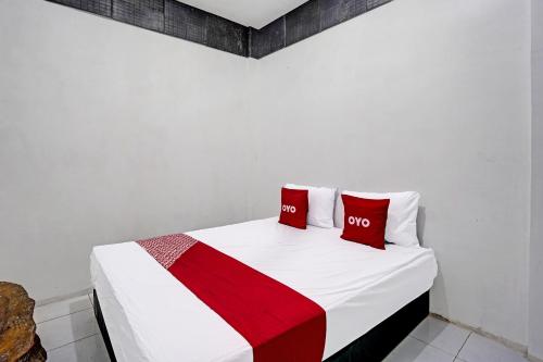 a white bed with two red pillows on it at Hotel O Villa A1 in Tretes