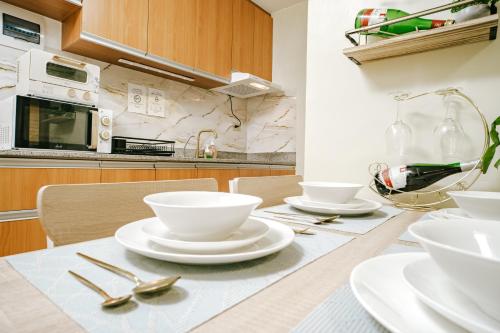 a kitchen with a table with white dishes on it at AR08 Smart Fully Furnished 1BR Condo in Davao City