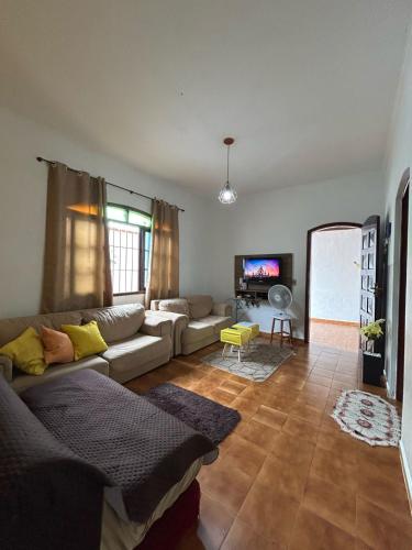 a living room with a couch and a tv at Aconchego pé na areia in Praia Grande