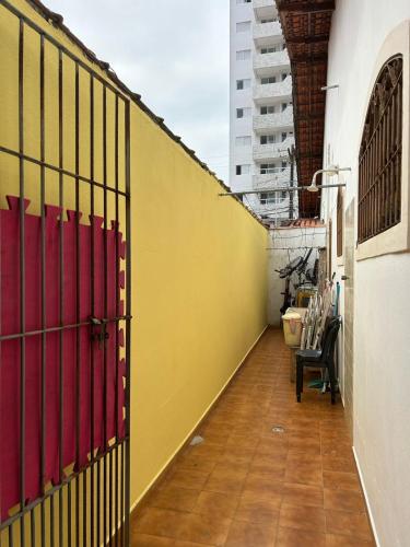 a room with a yellow wall and a fence at Aconchego pé na areia in Praia Grande