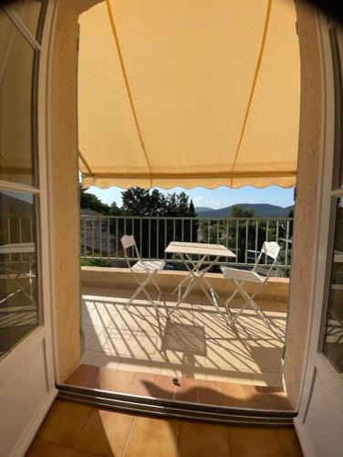 an open door to a balcony with a table and chairs at Piscine 2 in Plan-de-la-Tour