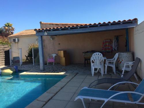 une terrasse avec une piscine, une table et des chaises dans l'établissement les hirondelles, à Bessan