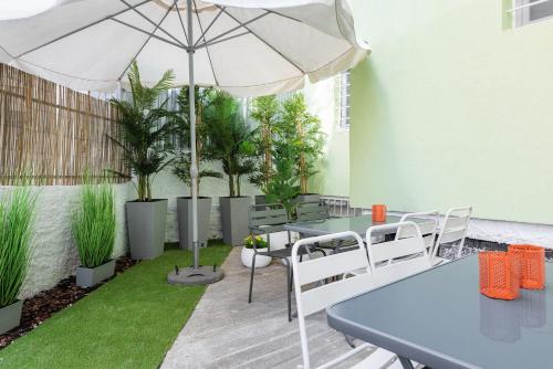 a patio with tables and chairs and an umbrella at Garden Suites in Thessaloniki