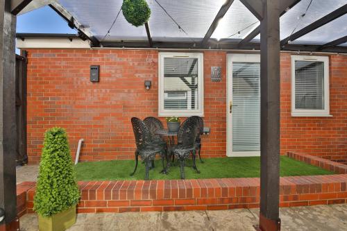 a patio with chairs and a table in a brick house at Luxury Cosy Central Detached Cardiff Bungalow with Free Parking in Cardiff